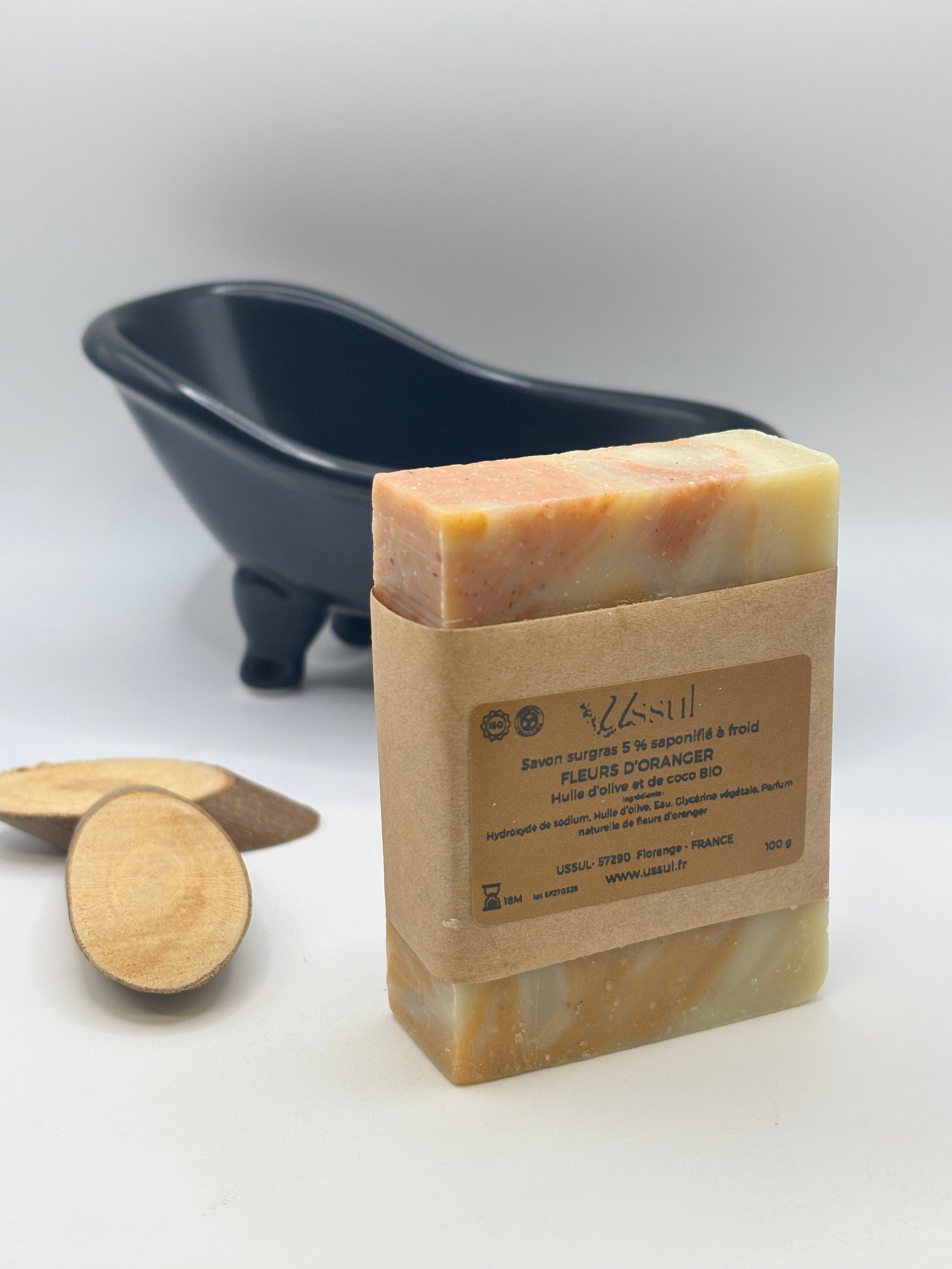 Savons artisanaux Ussul saponifiés à froid, présentés dans des pochons organza blancs, avec un savon Fleurs d’Oranger mis en avant sur un petit chevalet en bois.